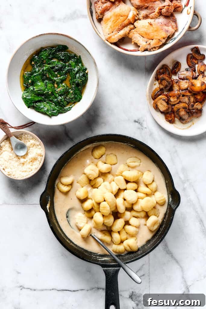 Velvety Chicken Gnocchi Delight 6 Gnocchi being added to the creamy sauce in a skillet, next to separate dishes of spinach, mushrooms, and chicken.
