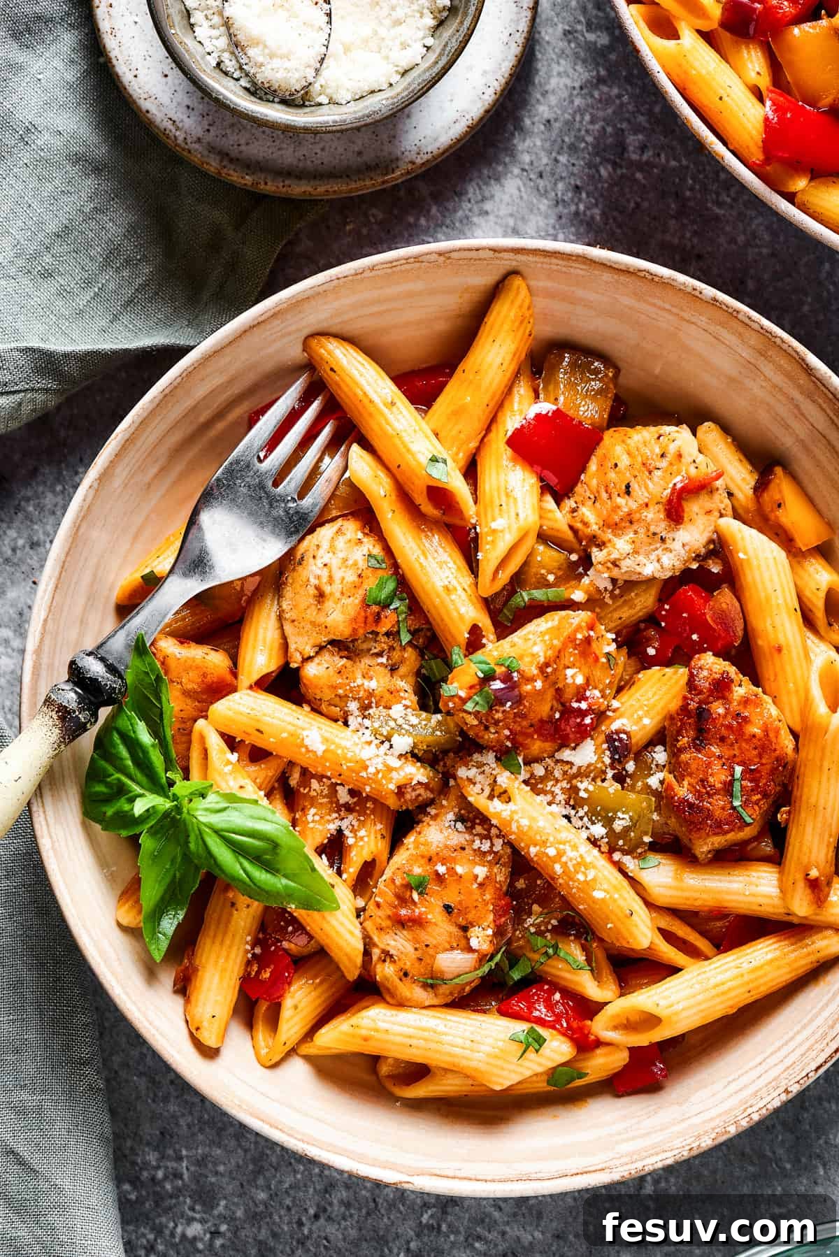 A fork taking a bite from a bowl of hearty Chicken Fajita Pasta, showcasing the blend of penne, chicken, and colorful vegetables.