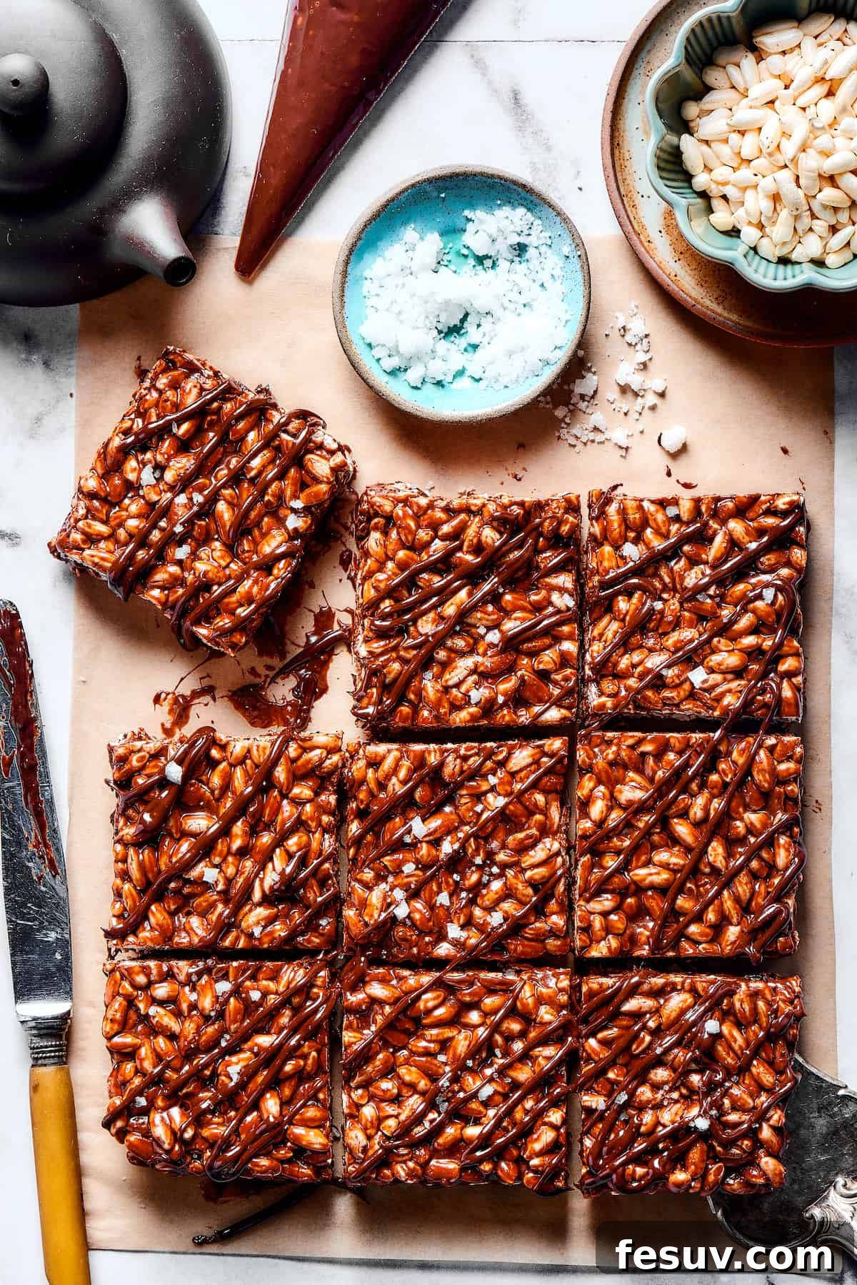 Chocolate Rice Krispie Treats are light and crunchy, with a sticky marshmallow texture and real dark chocolate. Easy and scrumptious! Squares of chocolate rice krispie treats next to a bowl of flaky sea salt.
