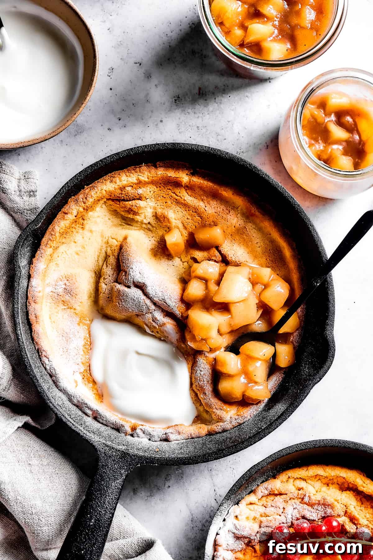 This old-fashioned Dutch Baby Pancake made in a cast-iron skillet is an easy, popover-like breakfast with homemade apple pie filling. Yum! Overhead shot of German pancake in a cast iron skillet.