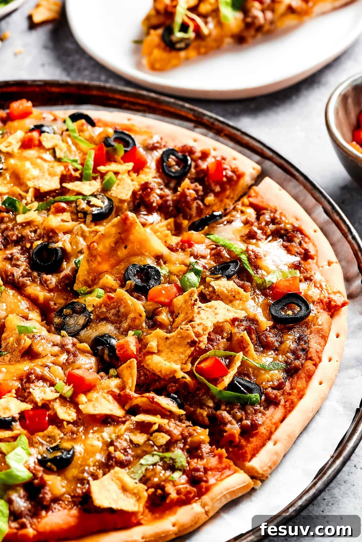Customize your Mexican pizza with a variety of fresh toppings. A close-up view of a homemade Mexican pizza adorned with vibrant shredded lettuce, crispy crushed tortilla chips, diced tomatoes, and other fresh toppings, ready to be served.