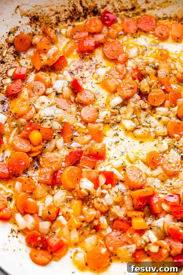 This one pot chicken and rice recipe is a whole meal - tender, pan seared chicken thighs, sautéed veggies, and creamy rice. So good! frying carrots and onions in a white skillet