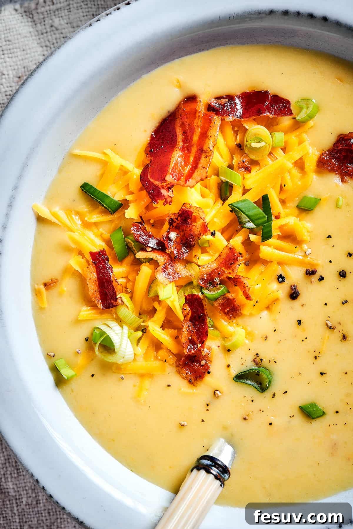 Ultimate Cheesy Bacon Potato Soup 13 Another close-up of the inviting loaded baked potato soup, adorned with a generous sprinkle of crispy bacon, vibrant green onions, and melted cheese, inviting a comforting spoonful.