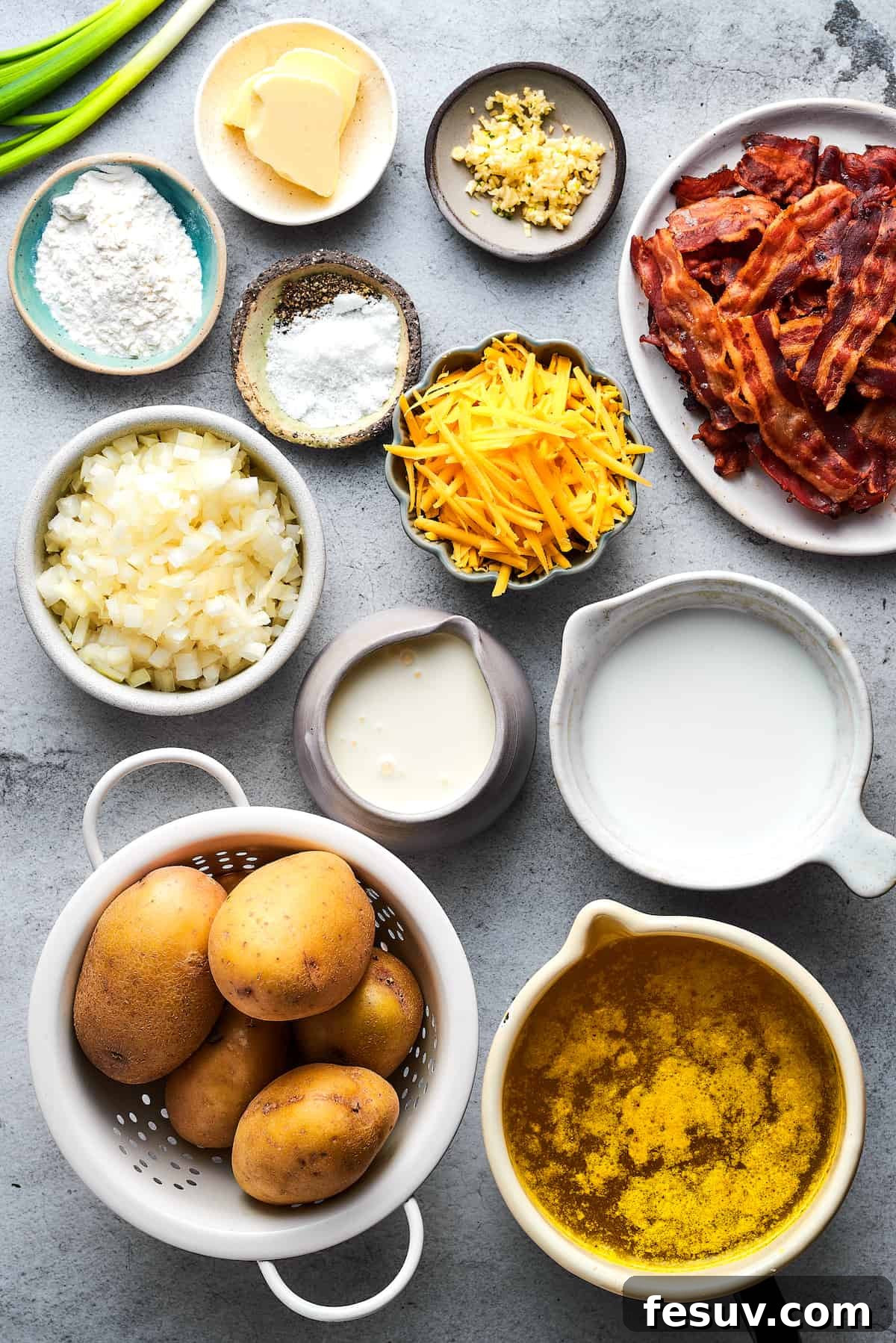 Ultimate Cheesy Bacon Potato Soup 4 All the fresh ingredients for homemade baked potato soup laid out neatly on a kitchen counter, including potatoes, butter, onion, garlic, milk, half-and-half, broth, cheddar cheese, and seasonings.