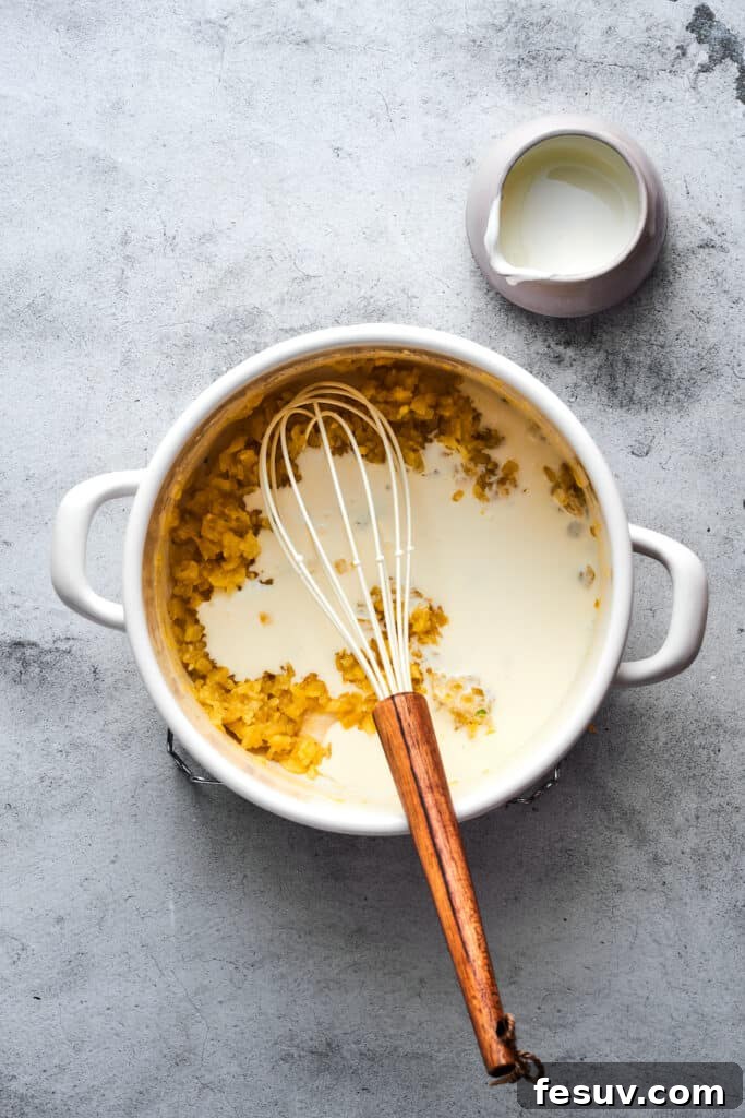 Ultimate Cheesy Bacon Potato Soup 8 A whisk vigorously mixing milk into a soup pot, combining with the roux to create a smooth, creamy base.