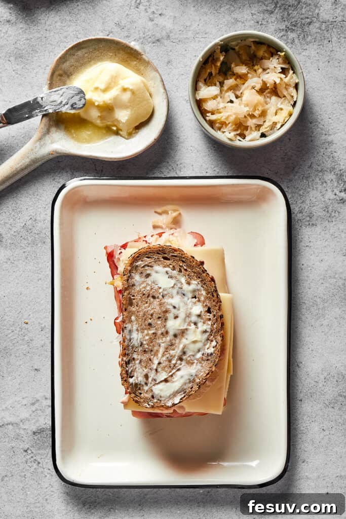A fully assembled, un-grilled Reuben sandwich showcasing its layers of rye bread, melted Swiss cheese (unmelted in this stage), savory corned beef, tangy sauerkraut, and creamy Russian dressing, ready for the skillet.