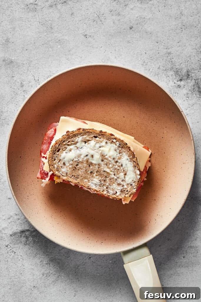 A classic Reuben sandwich sizzling on a hot skillet, with the buttered rye bread achieving a perfect golden-brown crust and the Swiss cheese visibly melting, cooked under a lid for even heat distribution.