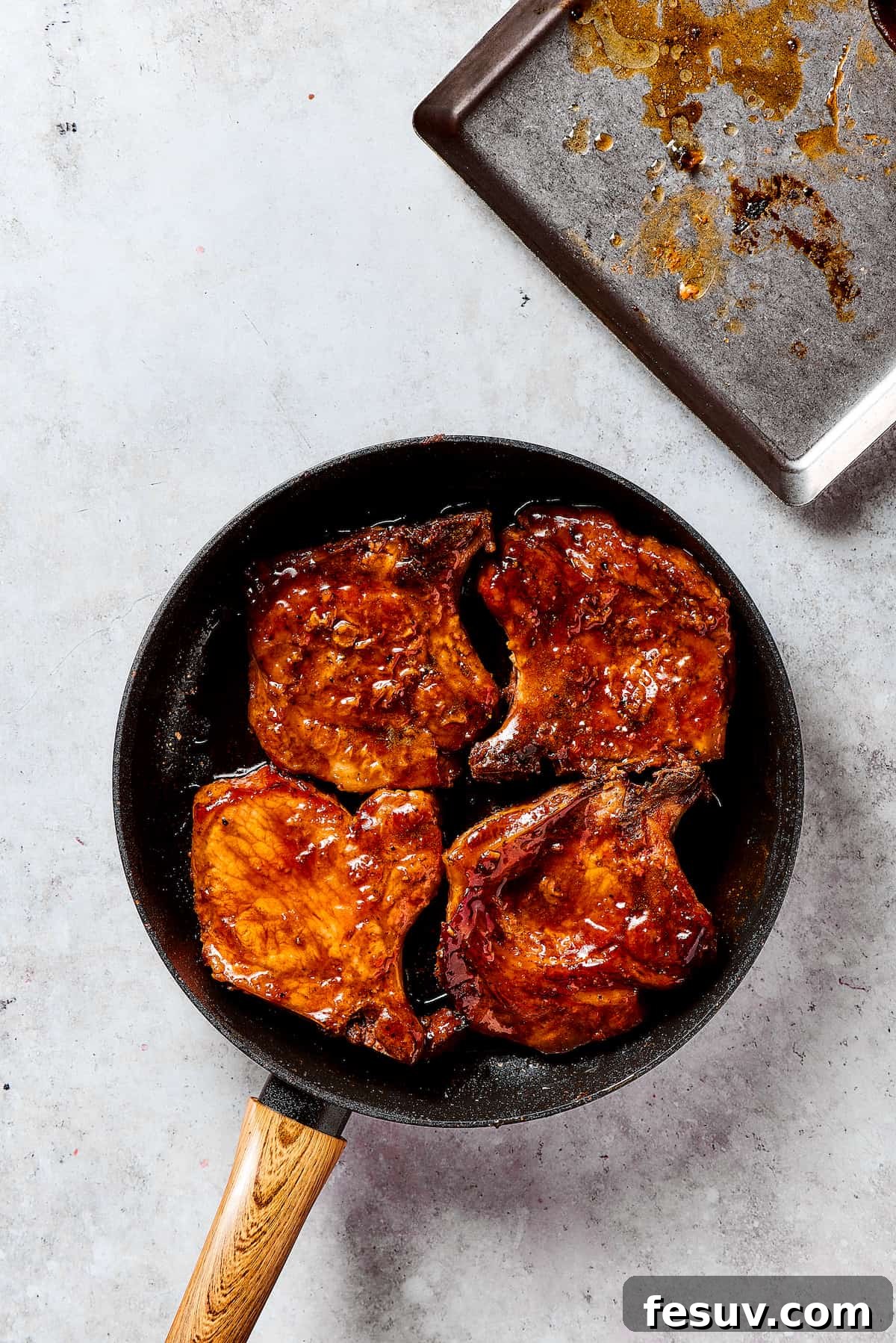 Pork Chops Glazed in Brown Sugar Sauce A close-up of pork chops being glazed in the rich brown sugar sauce in a skillet.