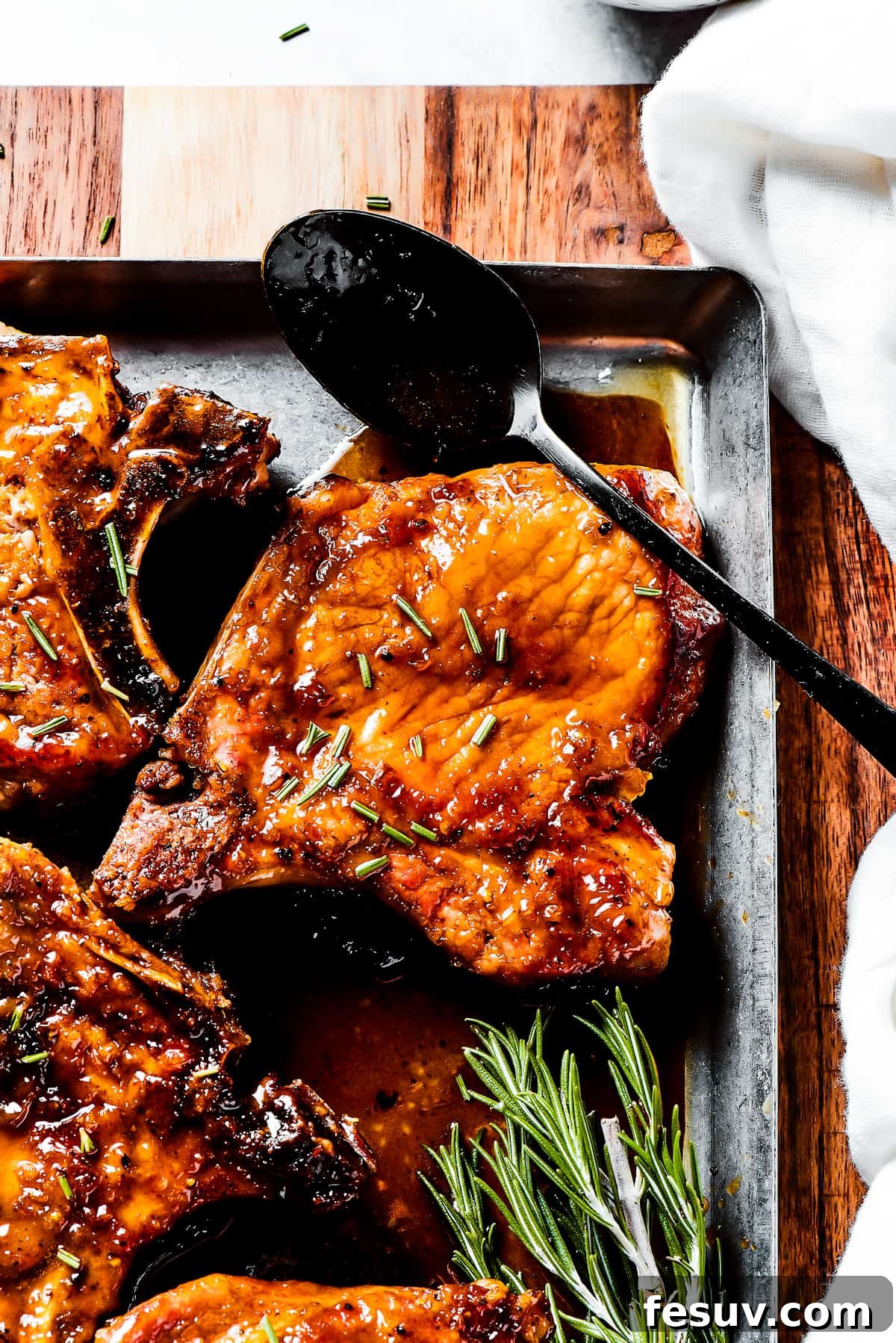 Glazing Pork Chops with Brown Sugar Sauce A hand spoons the rich brown sugar glaze over pan-fried pork chops.