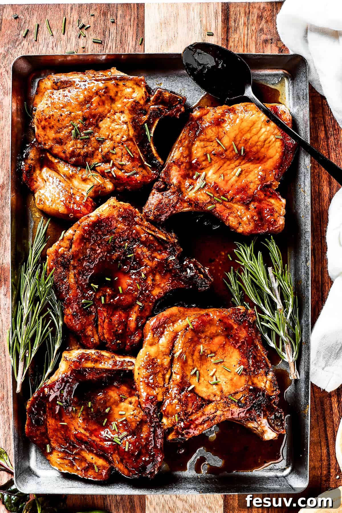 Juicy Pan-Fried Pork Chops with Irresistible Brown Sugar Glaze A tray of perfectly cooked brown sugar pork chops with a sprinkle of fresh herbs, ready to be enjoyed.