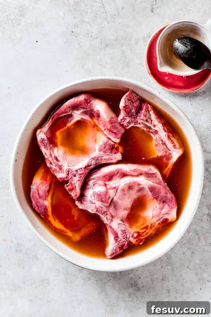 Pork Chops Soaking in Brine Pork chops submerged in a brining solution in a bowl.