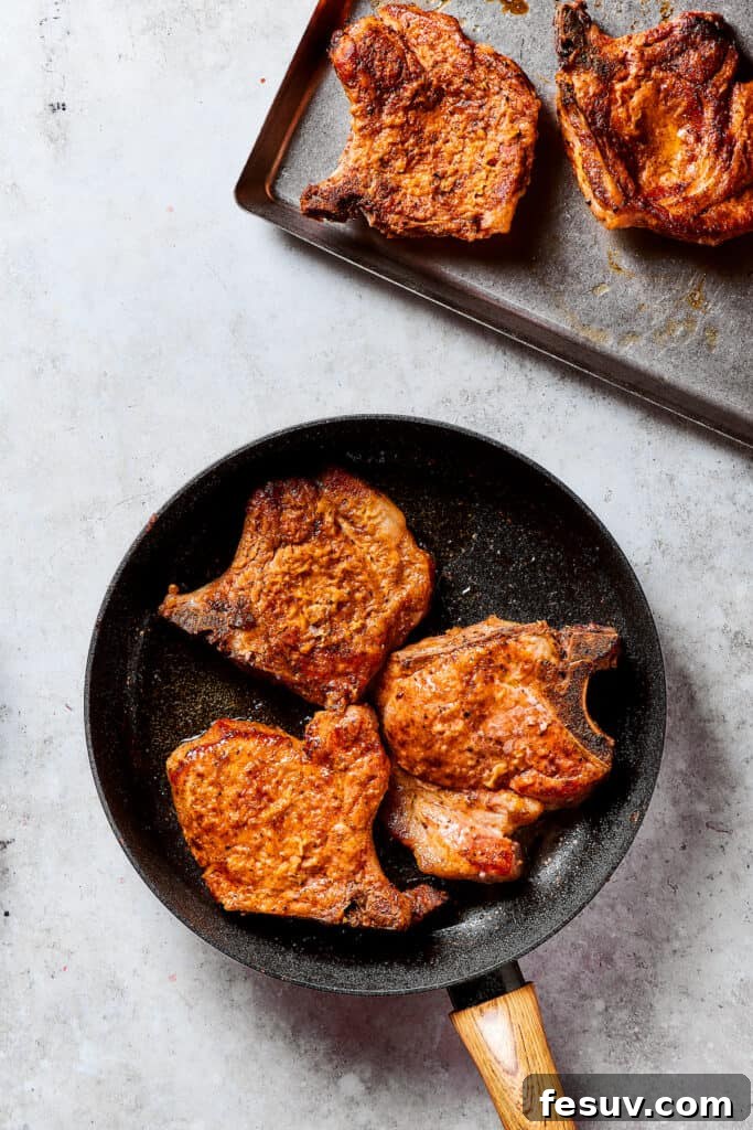 Pan-Fried Pork Chops Ready for Glazing Perfectly browned pork chops resting on a plate, with others still in the skillet.