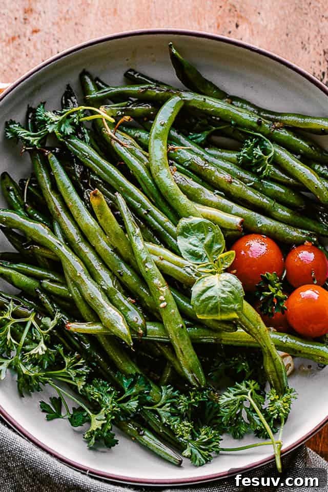 cooked green beans served in a bowl with fresh basil and cherry tomatoes