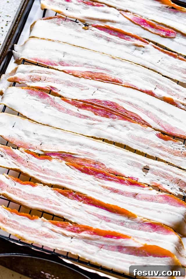 Raw bacon slices neatly arranged on an oven rack, ready for baking.