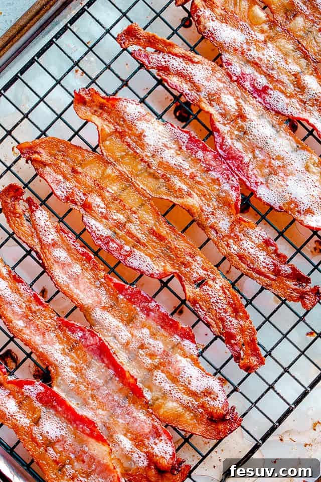 Oven baked bacon cooking on an oven rack, starting to crisp.