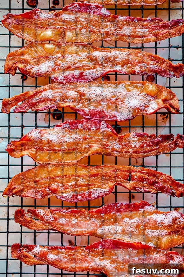 Oven baked bacon cooling on a wire rack, glistening and perfectly crispy.