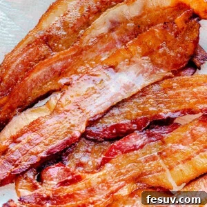Oven baked bacon on a paper towel, perfectly golden and crispy.