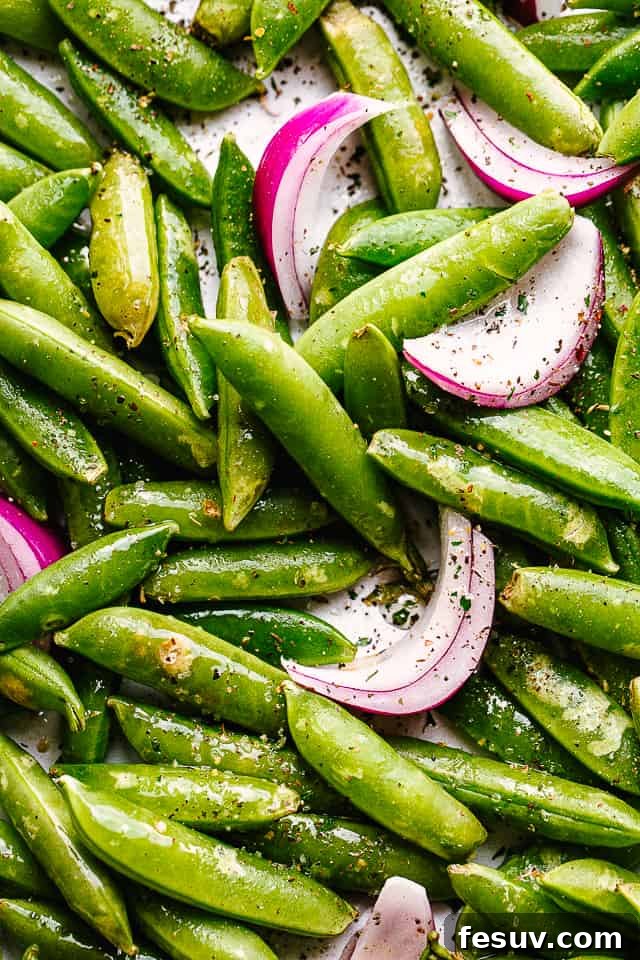 close up of raw snap peas and onions tossed with seasonings