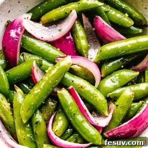 roasted sugar snap peas with red onions served in a cream bowl