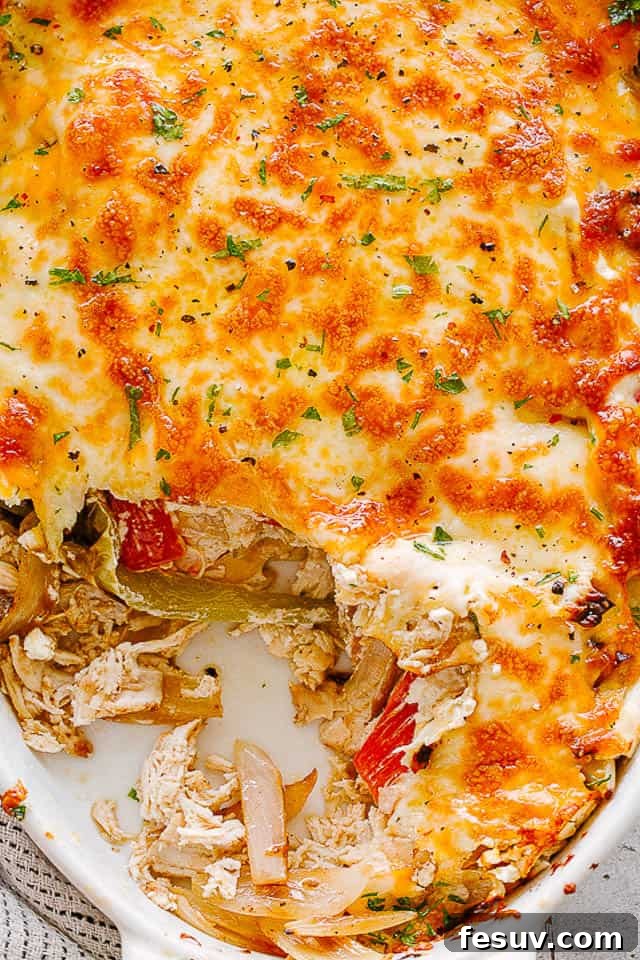 close up view of a chicken fajita casserole in a white oval baking dish