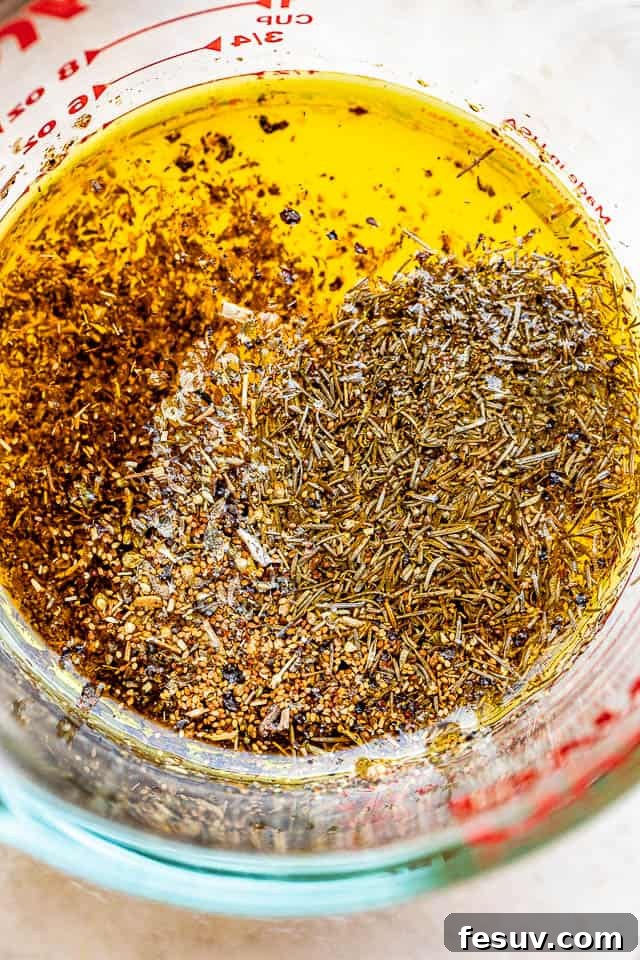 A glass measuring cup filled with a vibrant yellow lemon garlic herb marinade, ready to infuse flavor into the dish.