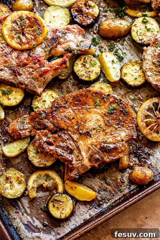 A vibrant sheet pan showcasing a complete meal of baked pork chops, roasted squash, and potatoes, ready to be served.