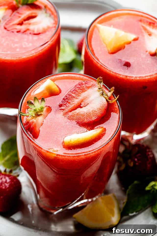 Pink Lemonade Berry Sangria 5 Short drinking glasses filled with vibrant Strawberry Lemonade Sangria, garnished with fresh strawberry slices and lemon wedges, ready for a summer party.