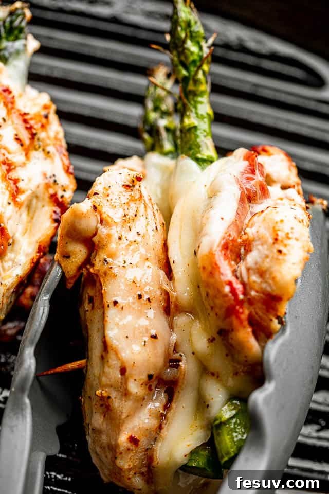 Chicken breast stuffed with prosciutto, cheese, and asparagus, held together with tongs