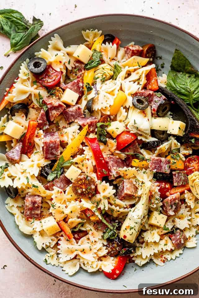 Italian Antipasto Pasta Salad top view of a large blue salad bowl with pasta, olives, cheeses, and salami
