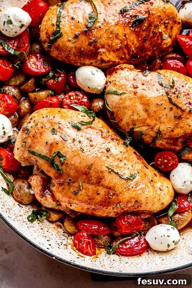 One Pan Tangy Balsamic Chicken with Golden Potatoes 6 top close up shot of chicken breasts brushed with balsamic vinegar and set next to cherry tomatoes, mozzarella cheese balls, and garnish of basil
