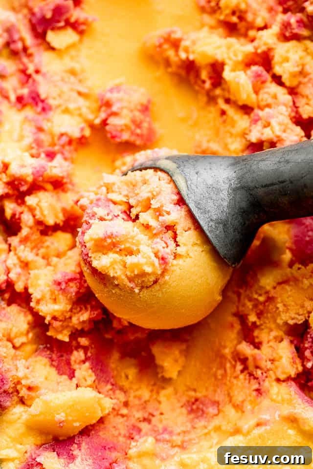 close up shot of mango strawberry frozen yogurt in an ice cream scoop