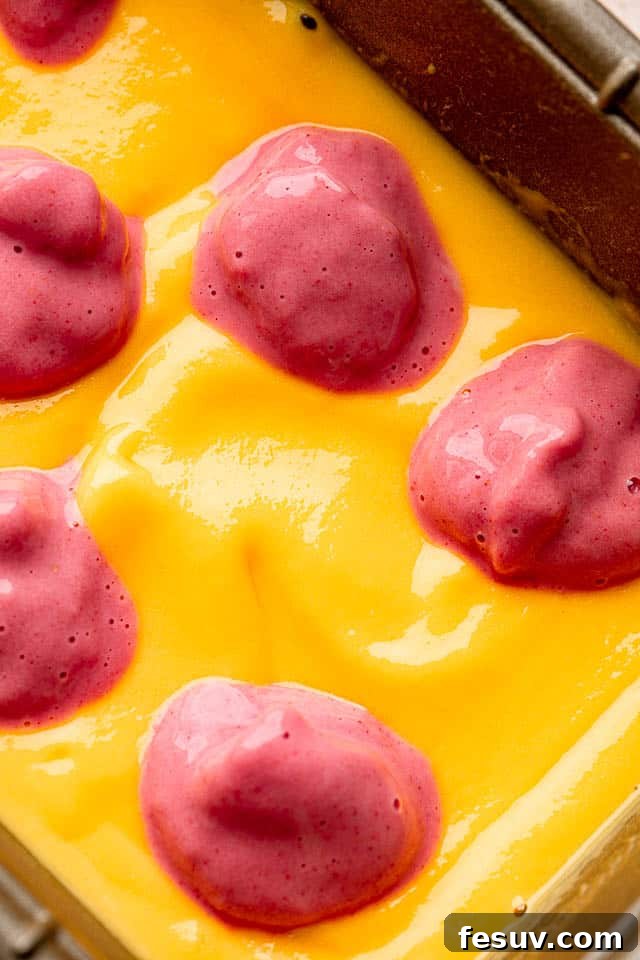 close up shot of a blended mango mixture topped with dollops of blended strawberry mixture