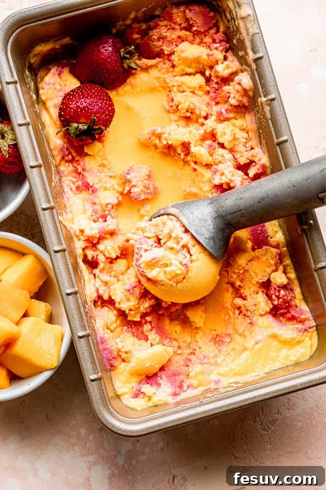 top shot of mango strawberry frozen yogurt in a loaf pan with ice cream scooper