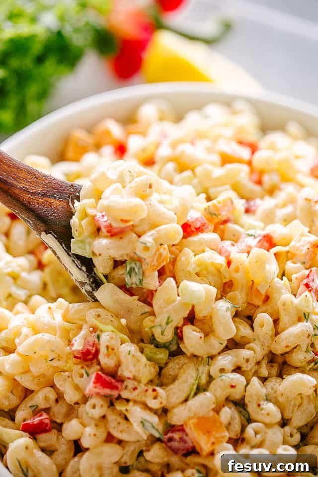 Close-up of a bowl of macaroni salad with a spoon.