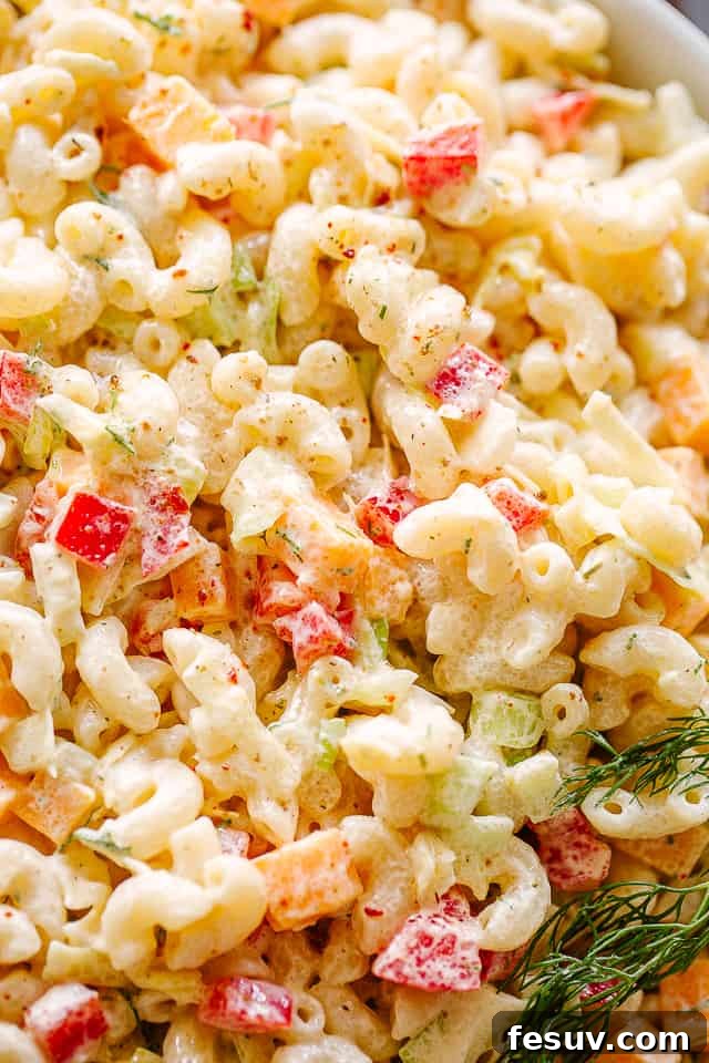 Close up of macaroni salad, showing creamy texture and visible vegetables.