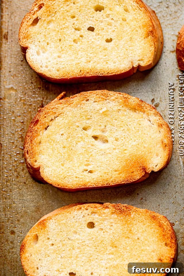 Overhead view of several slices of perfectly toasted Italian bread, golden brown and ready for garlic infusion.