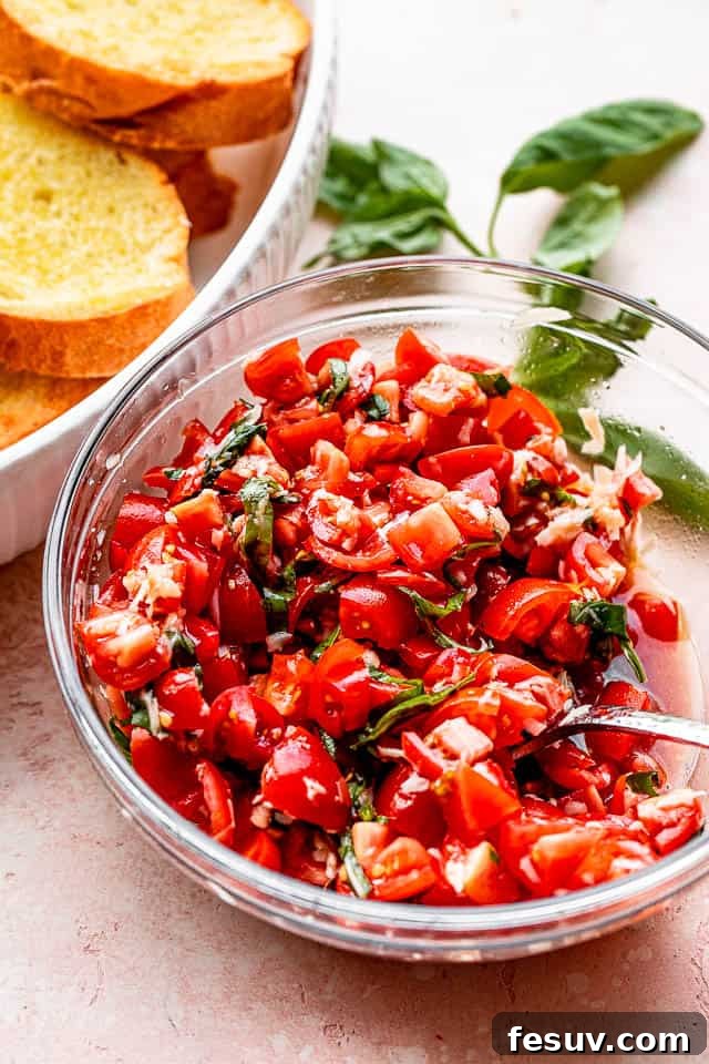 A vibrant bowl of fresh tomato and basil salad, with diced tomatoes, green basil ribbons, and a hint of parmesan, set next to the toasted garlic bread slices.