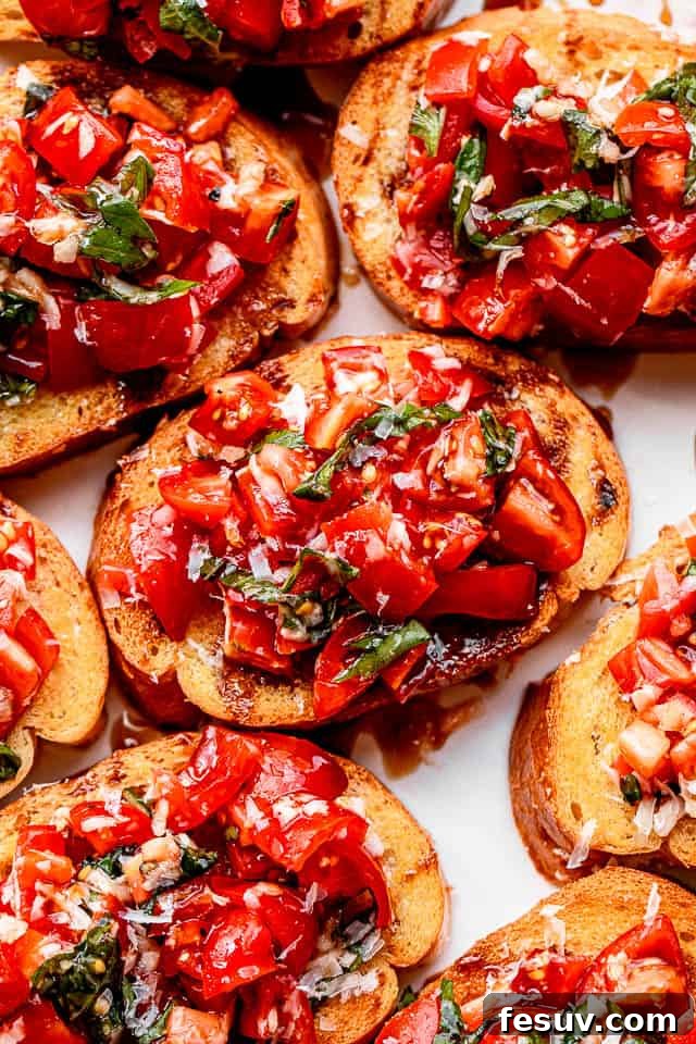 A close-up shot of a single piece of garlic bread bruschetta, showing the vibrant red diced tomatoes, green basil, and golden toasted bread.