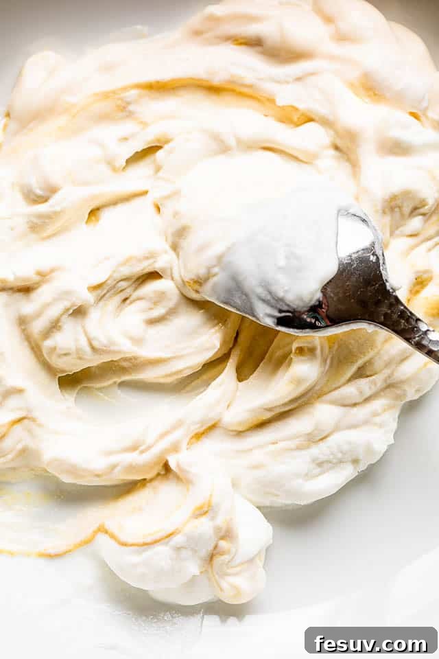 Silver spoon stirring and preparing a creamy dressing in a white bowl