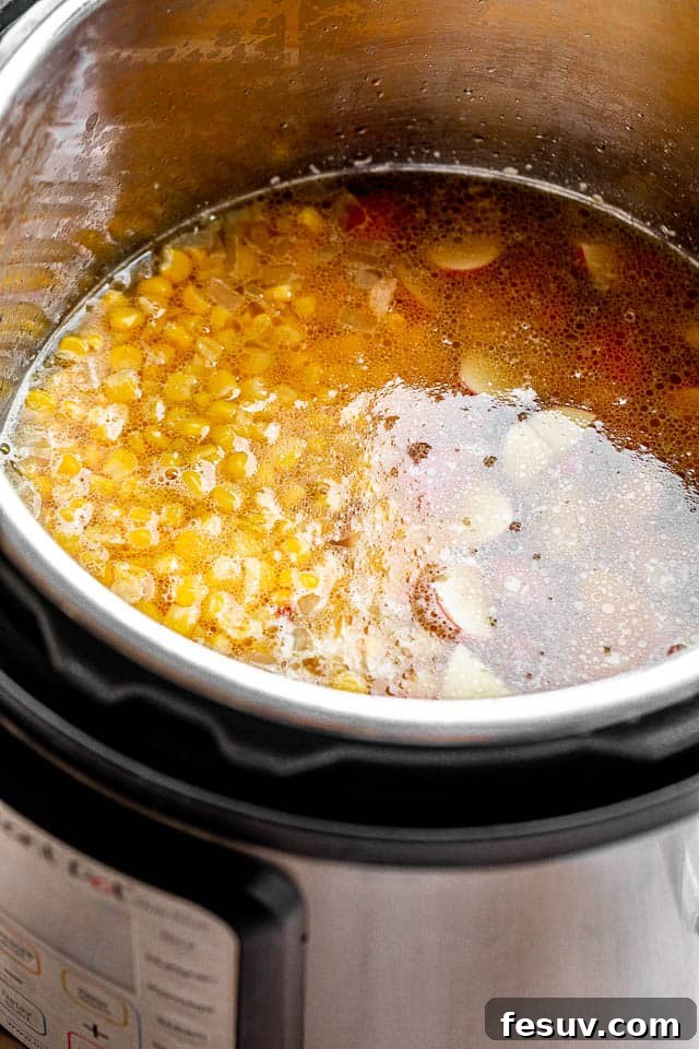The inside of an Instant Pot with corn chowder cooking, showcasing the simmering ingredients before the final cream and cheese are added.