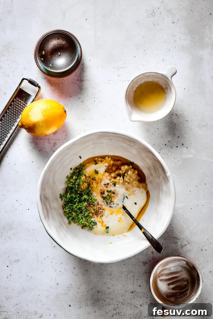 Mixing the vibrant yogurt marinade for tender chicken. A close-up shot of a white bowl where creamy yogurt, olive oil, lemon zest, herbs, and spices are being whisked together to form the chicken marinade.