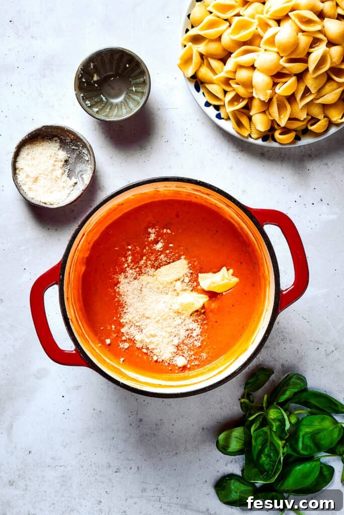 A generous amount of Parmesan cheese being added to the creamy vodka sauce, enhancing its richness.