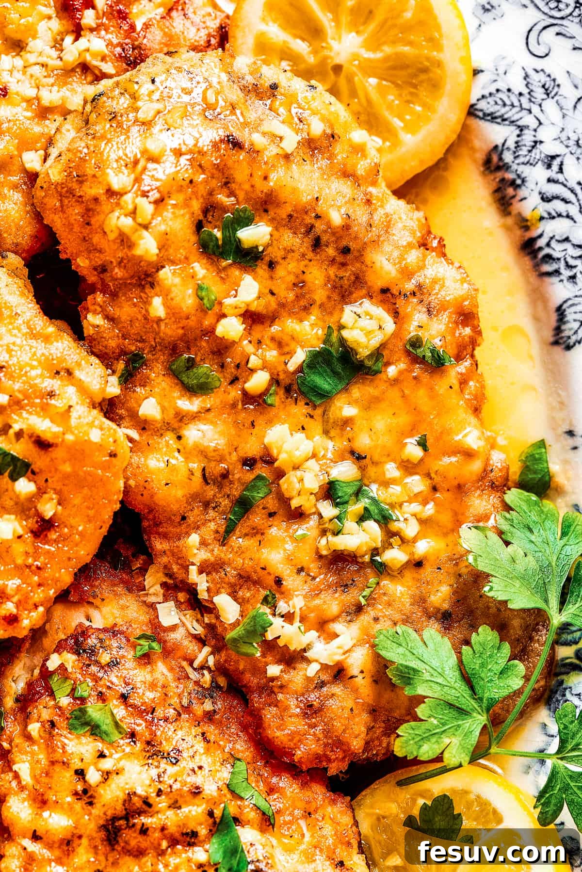 A close-up of a delectable Lemon Chicken Recipe: Crispy, parmesan-crusted chicken with real lemon butter sauce. A close-up shot of a succulent lemon chicken breast, artfully arranged on a platter and garnished with fresh lemon wedges.