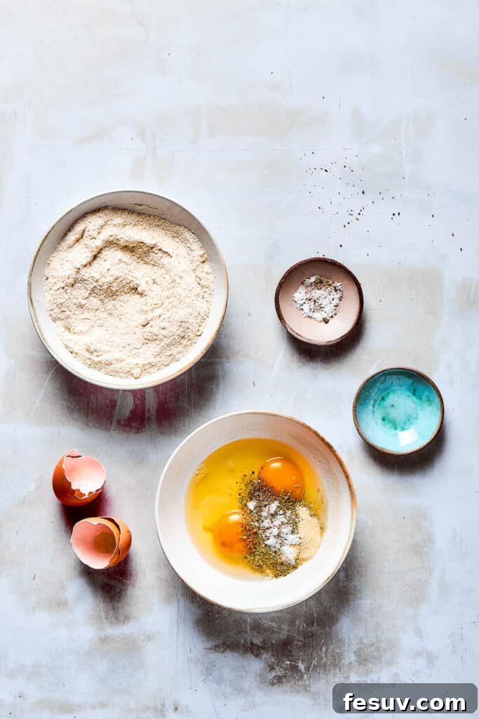 The secret to amazing Lemon Chicken: Crispy, parmesan-crusted chicken with real lemon butter sauce. A bowl of dry breading ingredients next to a bowl of beaten eggs seasoned with garlic powder and Italian seasoning.
