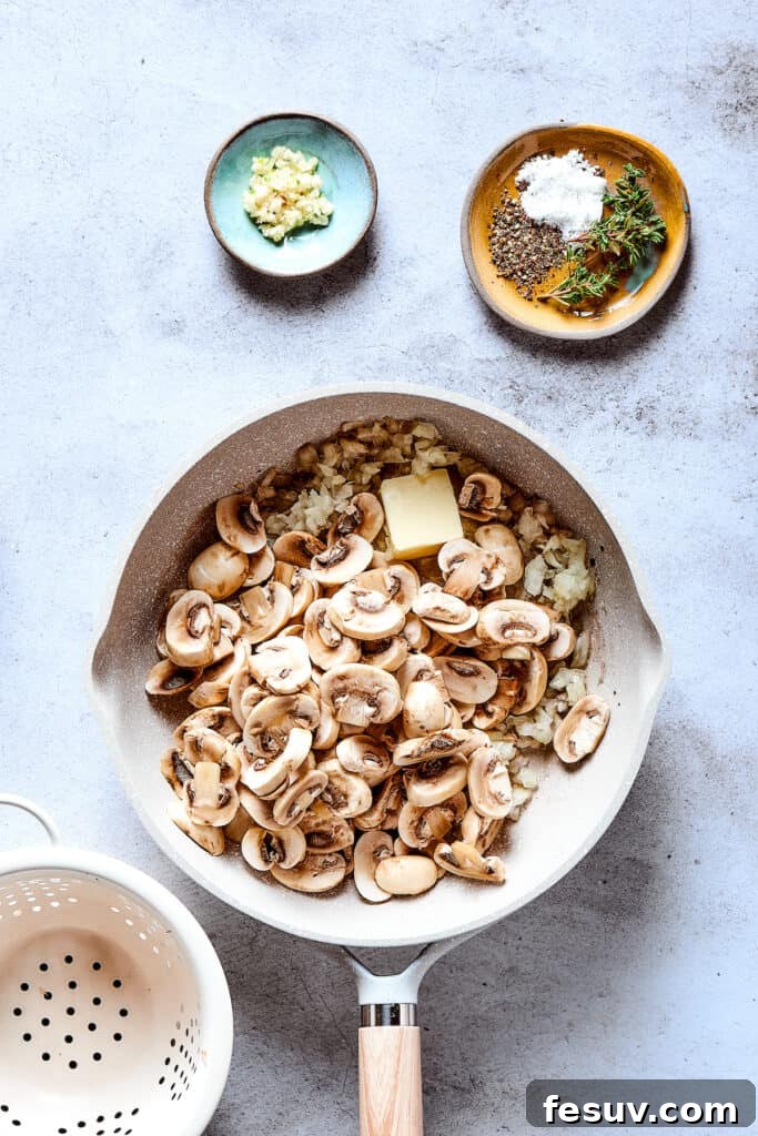 Sliced mushrooms are being added to the skillet with the sautéing onions and butter, beginning the process of building the mushroom gravy.