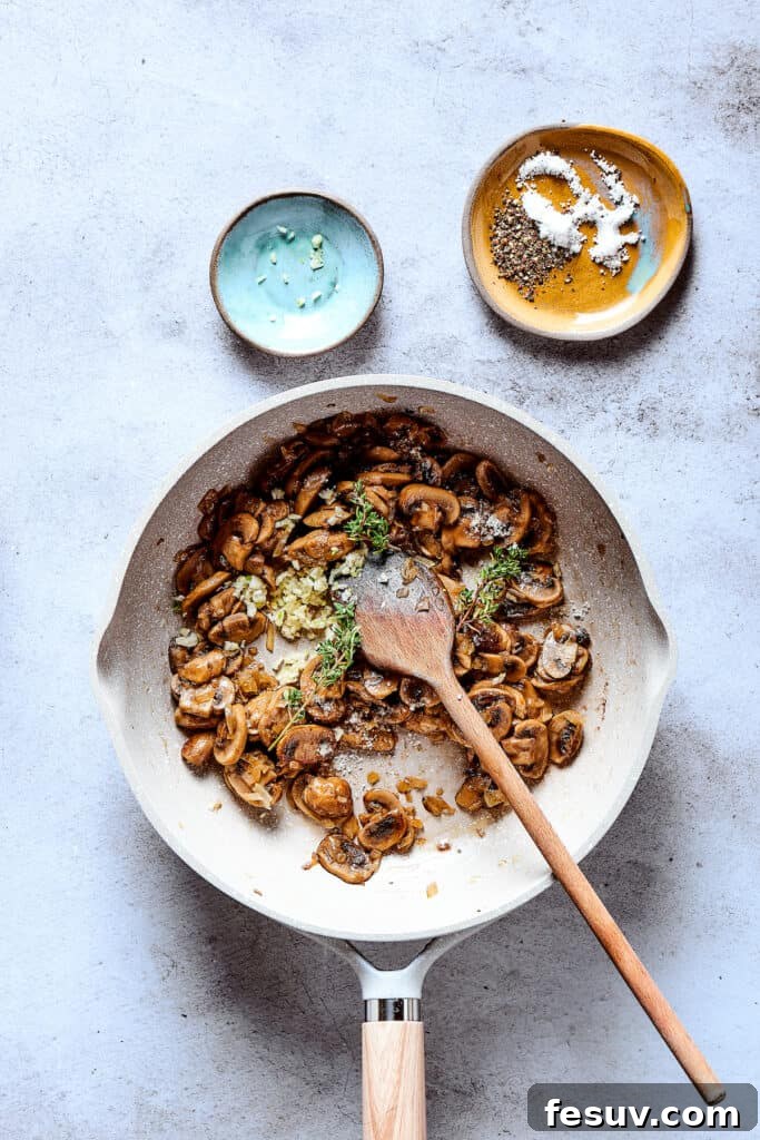 Garlic and thyme are mixed with the cooking onions and mushrooms in a skillet, infusing the vegetables with aromatic flavors for the gravy.