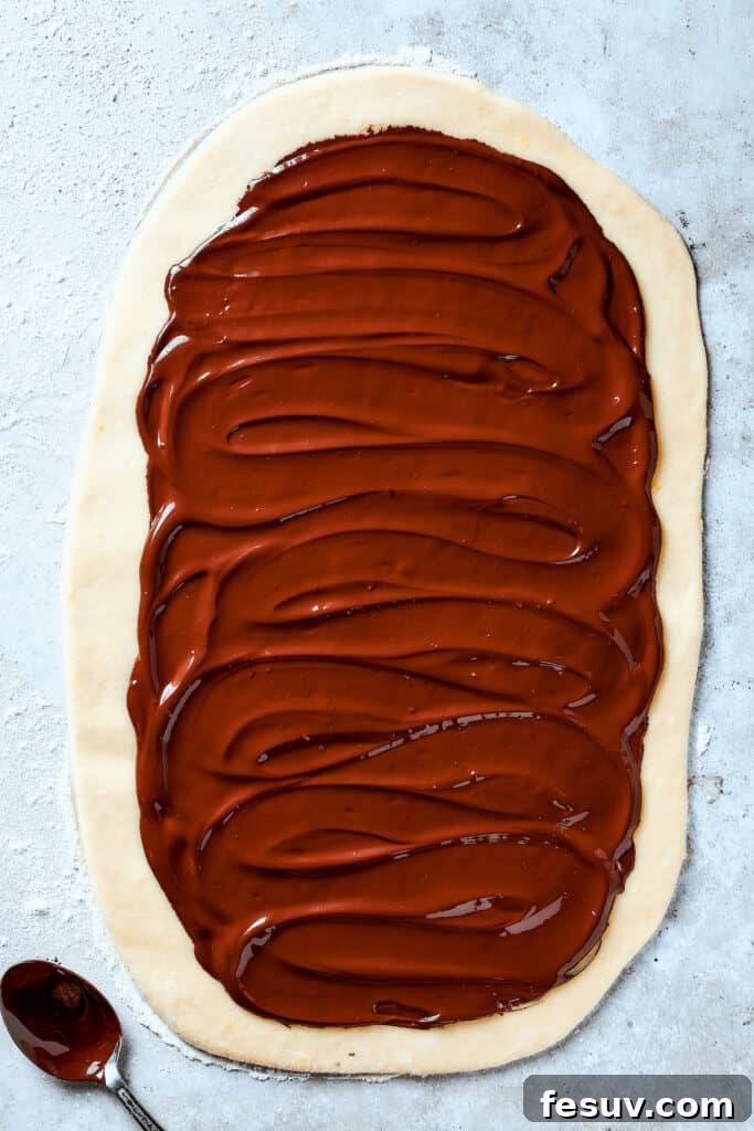 Chocolate spread out over a rectangle of dough.