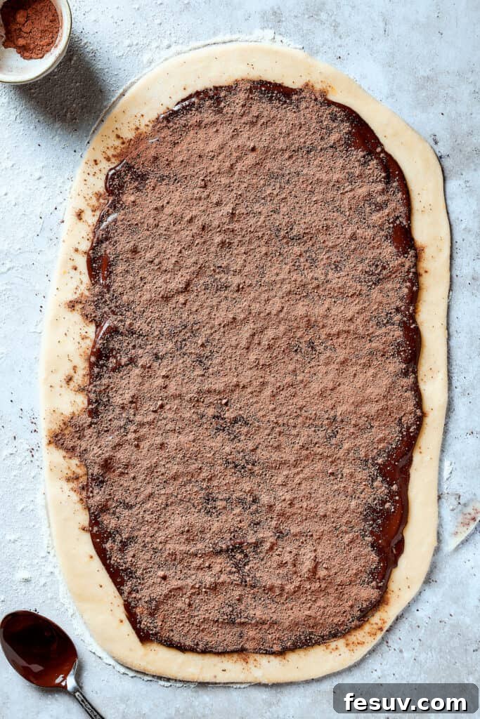 Chocolate spread out over a rectangle of dough and sprinkled with cocoa powder.