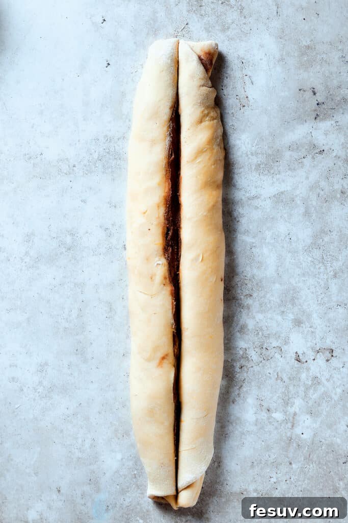 Slicing a roll of dough lengthwise.