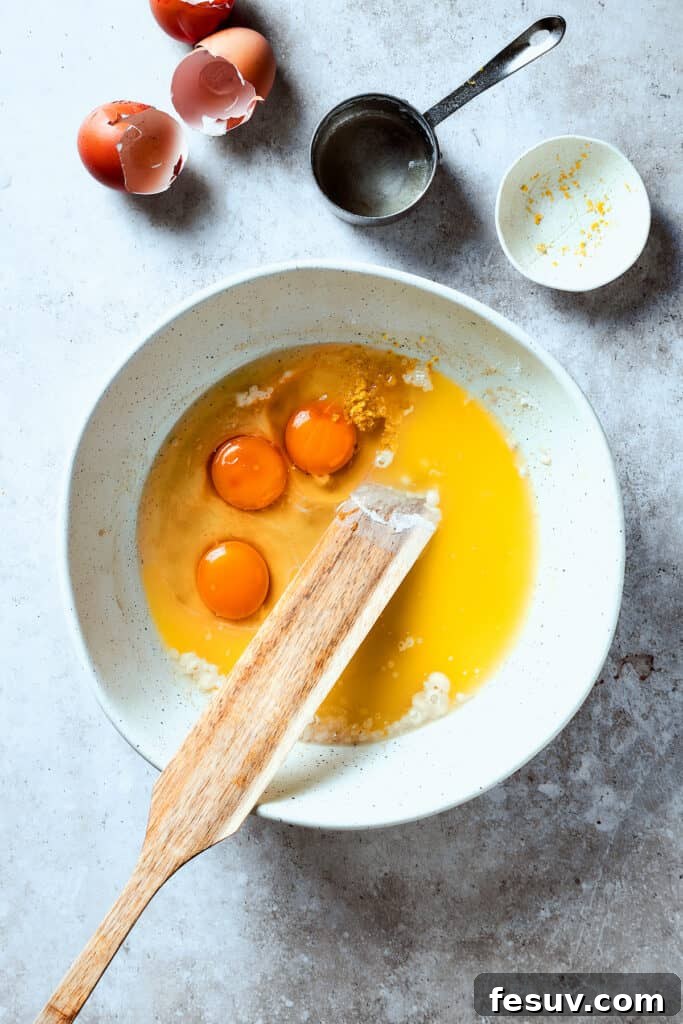 Stirring eggs into baking ingredients in a bowl.